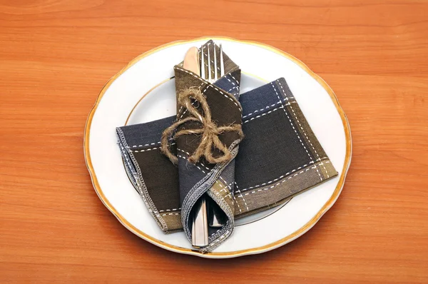 Cuchillo y tenedor en servilleta textil sobre mesa de madera —  Fotos de Stock