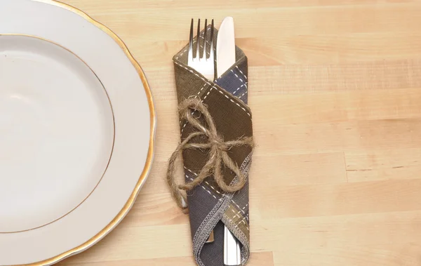 Nůž a vidličku v textilní ubrousek na dřevěný stůl — Stock fotografie