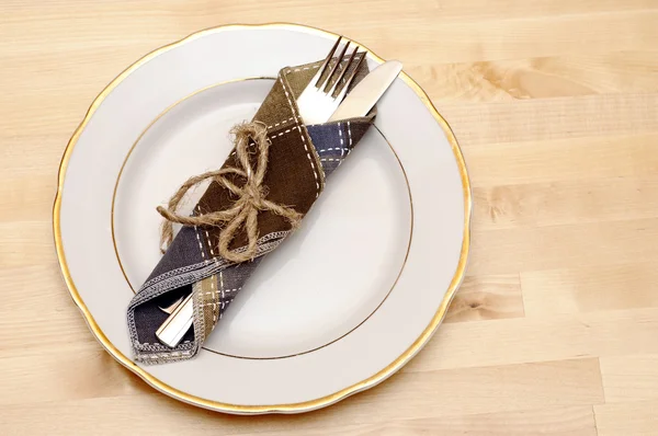 Knife and fork in textile napkin on wooden table — Stock Photo, Image