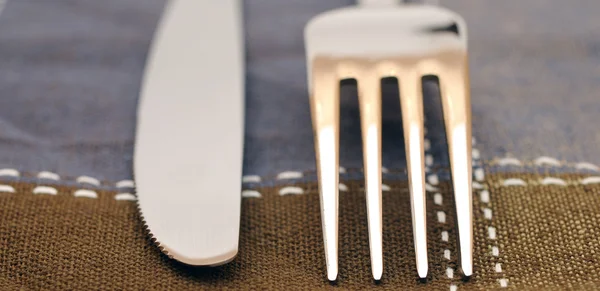 Närbild gaffel och kniv på textil servett — Stockfoto