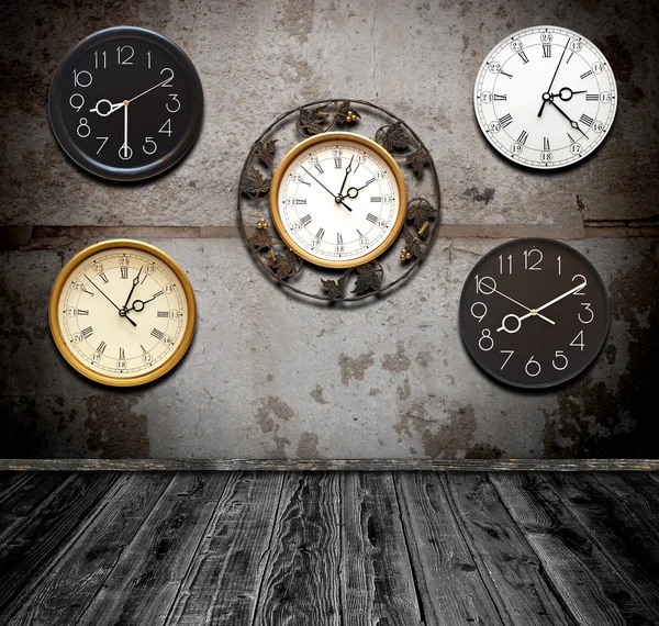 Коллекция настенных часов против стены в старой комнате — стоковое фото
