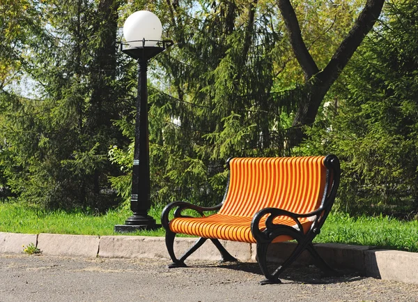 Bench under lamp in city park — Stock Photo, Image