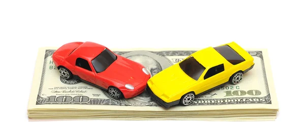 Spielzeugautos über viele Dollarscheine auf weißem Grund — Stockfoto