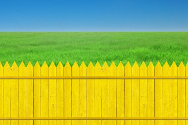 Yellow fence with grass on clear blue sky clipart