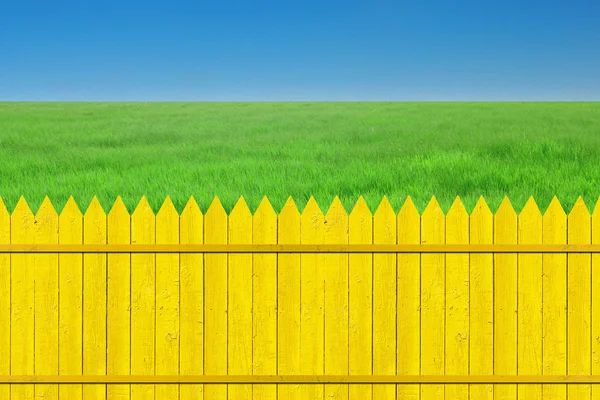 澄んだ青い空に草と黄色いフェンス — ストック写真