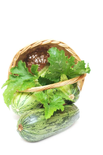 Frutas frescas de calabacín con hojas verdes y flores en la cesta —  Fotos de Stock