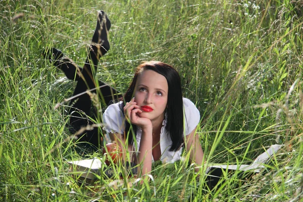 Chica en la hierba, con libros . Fotos De Stock