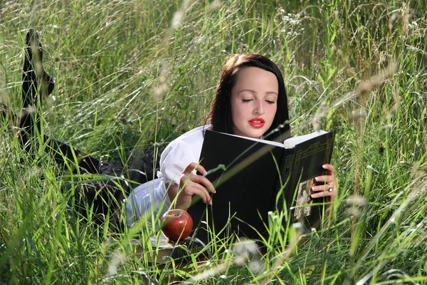 Mädchen auf Gras, mit Büchern. Stockbild