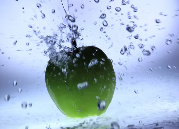 Färskt grönt äpple med vattenstänk — Stockfoto