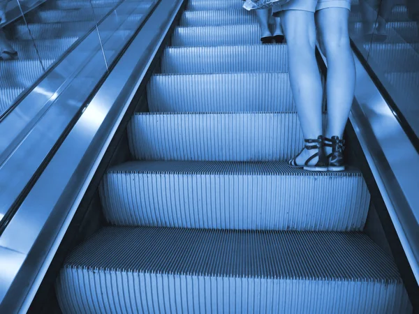 Κυλιόμενες σκάλες με γυναικεία πόδια — Φωτογραφία Αρχείου