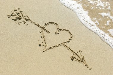 Heart pierced by Cupid's arrow drawn in the sand clipart