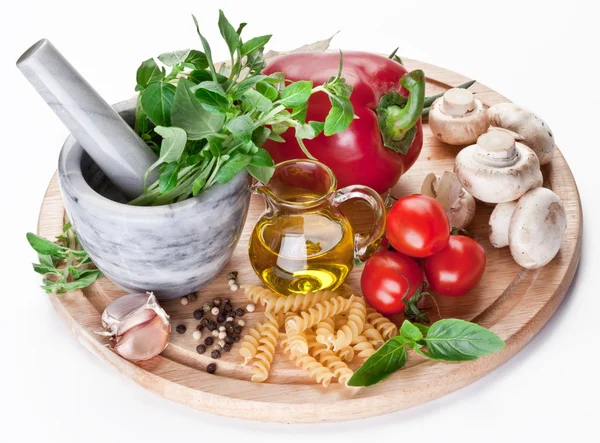 Mortar with pestle, basil herbs, olive oil and vegetables. — Stock Photo, Image