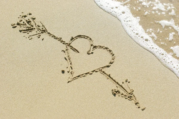 Srdce probodnuté Amorovým šípem nakresleným v písku — Stock fotografie