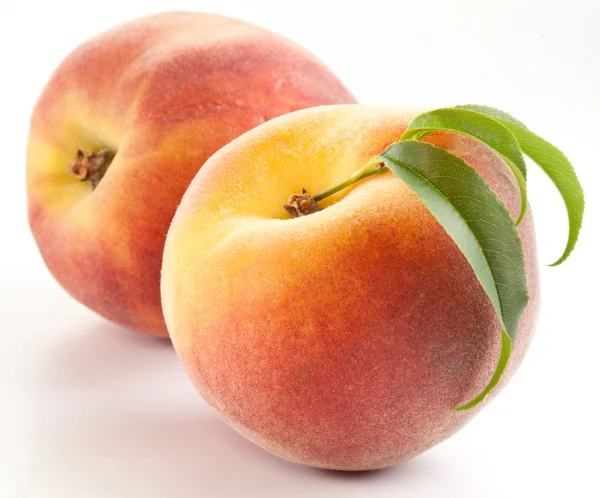 Два спелых персика с листьями — стоковое фото