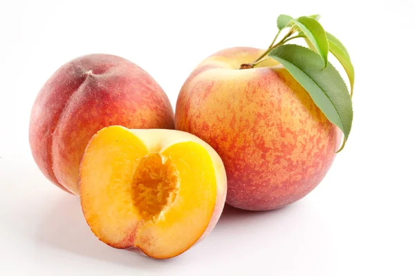 Стиглі персикові плоди з листям і скибочками — стокове фото