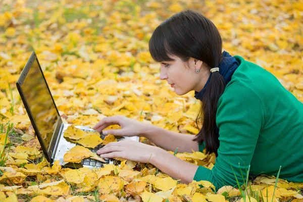 Schönes Mädchen ruht sich auf Herbstblättern aus — Stockfoto