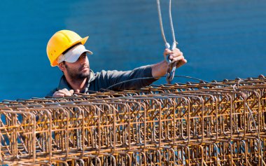 Construction worker loading stack of reinforcement beam cages to clipart