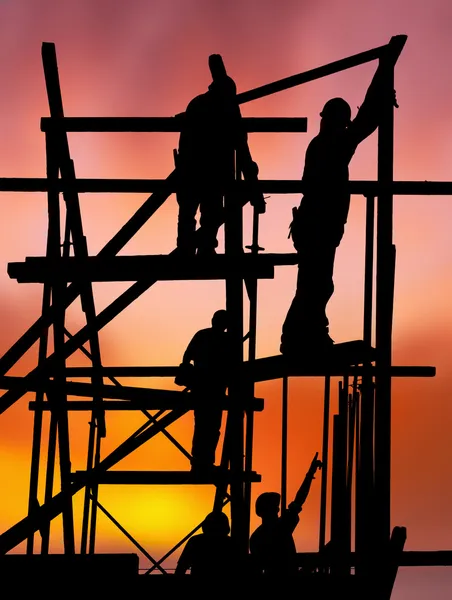 Byggnadsarbetare mot färgstark solnedgång — Stockfoto