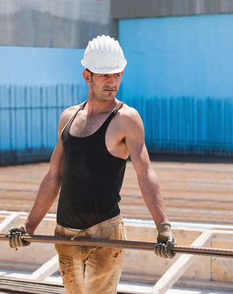 Trabalhador da construção civil transportando barras de aço de reforço — Fotografia de Stock