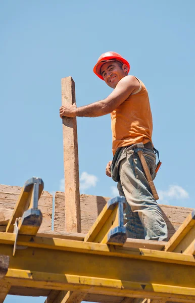 Uśmiechający się pracownik budowlany z deskowania belki — Zdjęcie stockowe