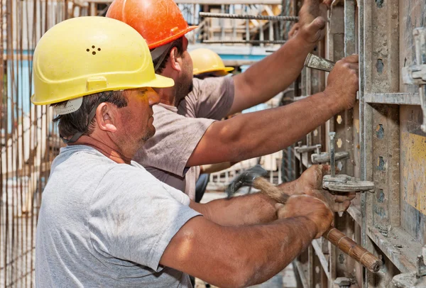 Construction workers positioning cement formwork frames — Stock Photo, Image
