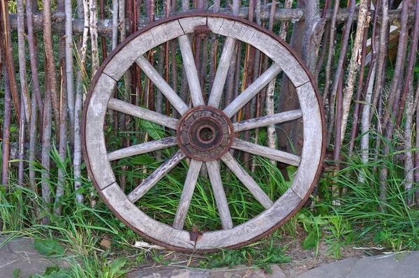 Roda de vagão velho único perto da cerca de madeira — Fotografia de Stock