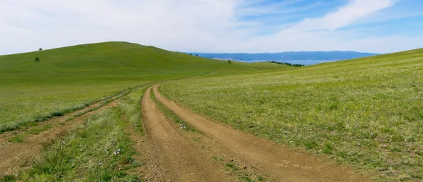 Καλοκαιρινό τοπίο με πράσινο γρασίδι, δρόμο και σύννεφα Εικόνα Αρχείου