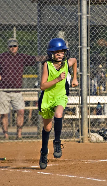 Jong meisje Softbal speler uitgevoerd naar het eerste honk — Stockfoto