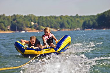 Boy and Girl Tubing Behind Boat clipart
