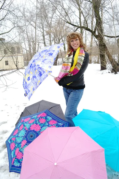 The girl in spring clothes with umbrellas on snow in the winter — Stock Photo, Image