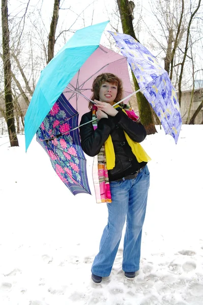 Das Mädchen in Frühlingskleidung mit Regenschirmen auf Schnee im Winter — Stockfoto