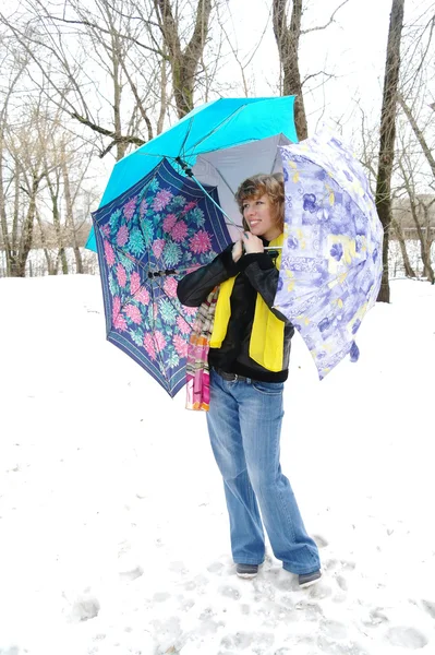 Dívka v jarním oblečení s deštníky na sněhu v zimě — Stock fotografie