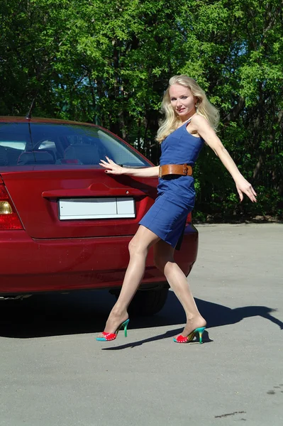 Девушка блондинка о красной машине летом — стоковое фото