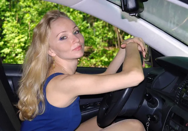 A menina a loira ao volante o carro no verão — Fotografia de Stock