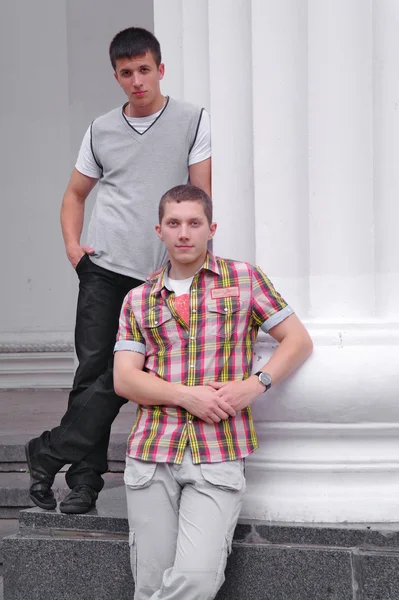 Двое юношей, окруженные белыми колоннами — стоковое фото