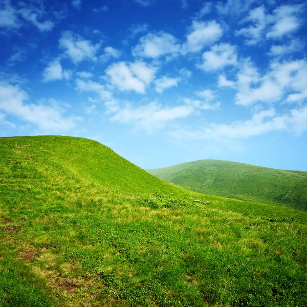 Zielone wzgórza i błękitne niebo z chmurami — Zdjęcie stockowe