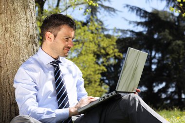 Man with computer in a park clipart