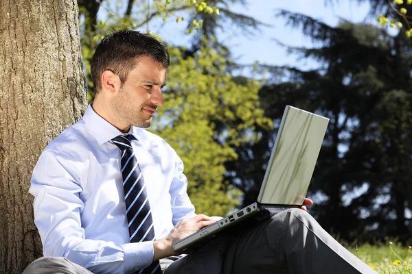 Mann med datamaskin i en park – stockfoto