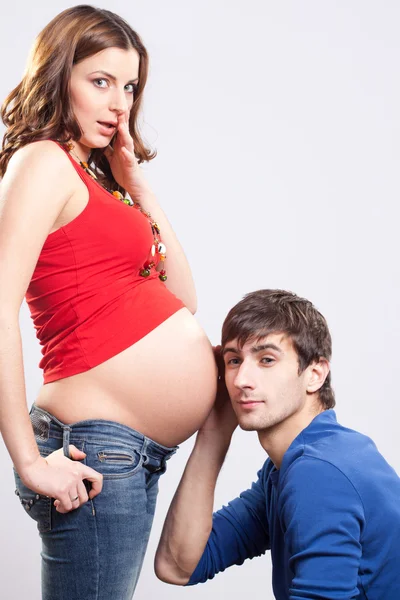 Gravid förvånad kvinna med man lyssna på magen — Stockfoto