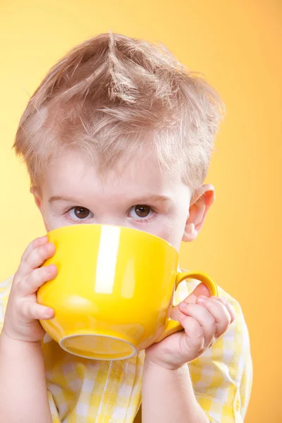 Смішний хлопчик п'є з великої жовтої чашки — стокове фото