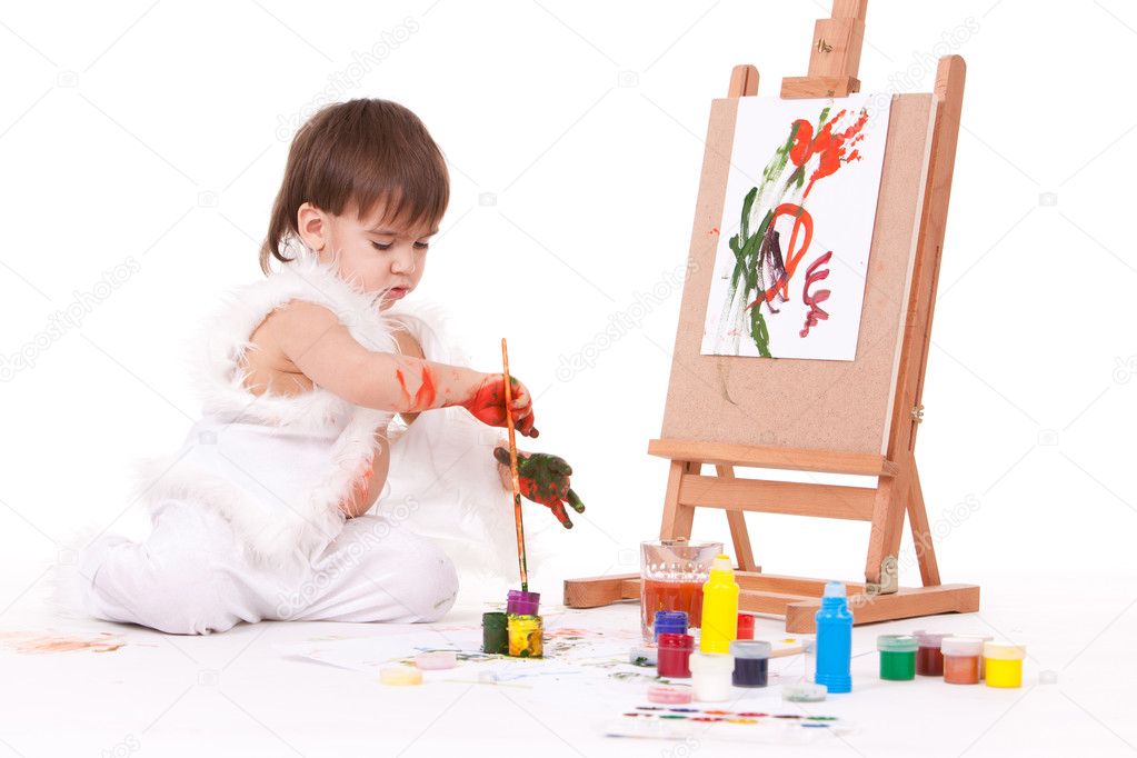 Cute baby painting with brush near easel