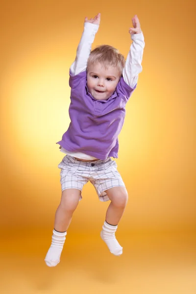 Salto feliz bonito menino em violeta t-shirt — Fotografia de Stock