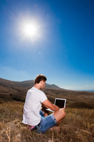 Человек работает на ноутбуке в горах — стоковое фото