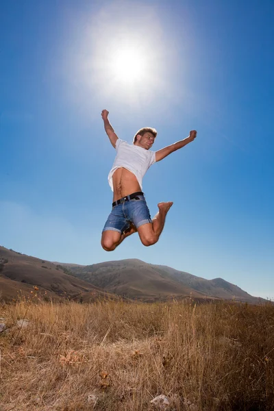 Skok szczęśliwy młody człowiek w górach — Zdjęcie stockowe