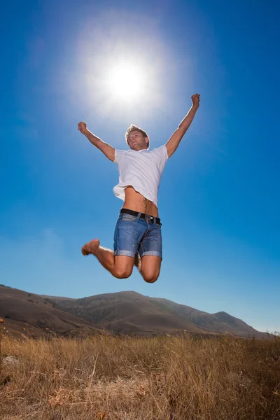 Щасливий молодий чоловік стрибає в горах — стокове фото