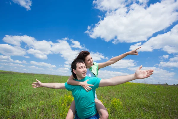 Szczęśliwa para młodych, wskazując na lato pole — Zdjęcie stockowe