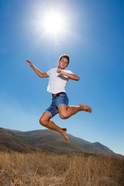 Glad ung man hoppa i bergen — Stockfoto