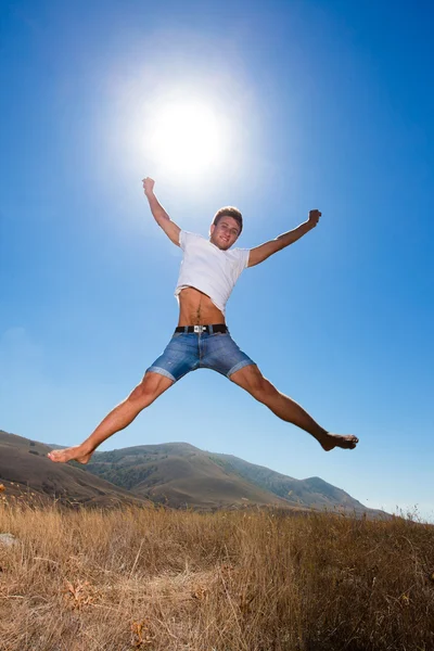Glücklicher junger Mann springt in die Berge lizenzfreie Stockfotos