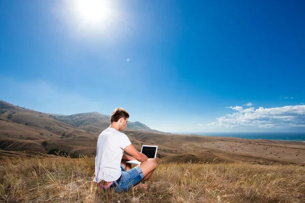 Homem trabalha em laptop nas montanhas — Fotografia de Stock