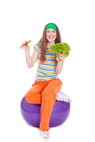 Smiling sporty woman on ball with heathy food — Stock Photo, Image
